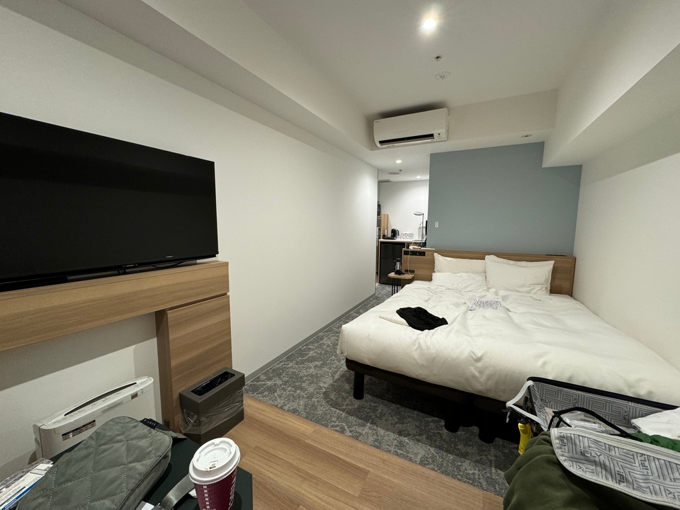 Intérieur d'une petite chambre d'hôtel avec un lit et une télé.