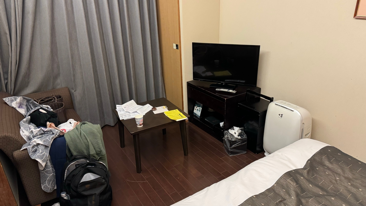 Chambre d'hôtel avec une table et un lit encombrés.