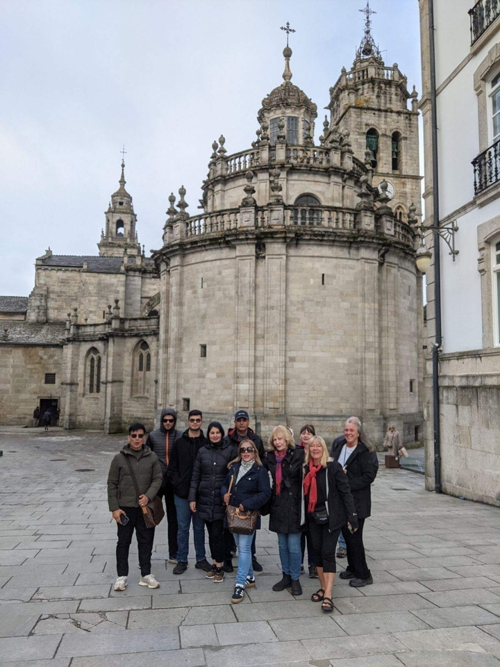 Groupe de personnes devant un bâtiment historique en pierre.
