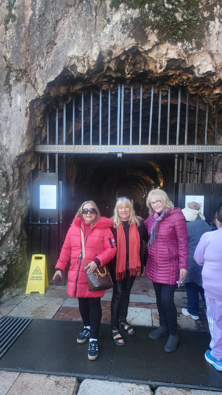 Des femmes posent devant l'entrée d'une grotte.