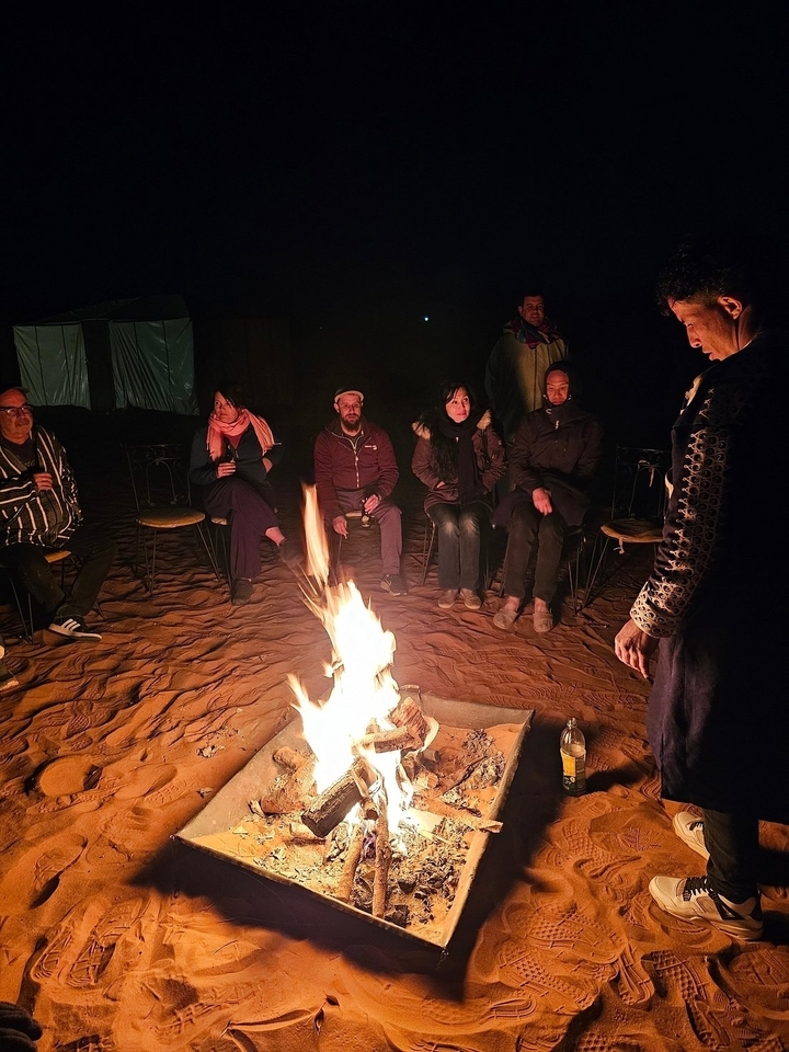 Groupe rassemblé autour d'un feu de camp dans le désert la nuit.