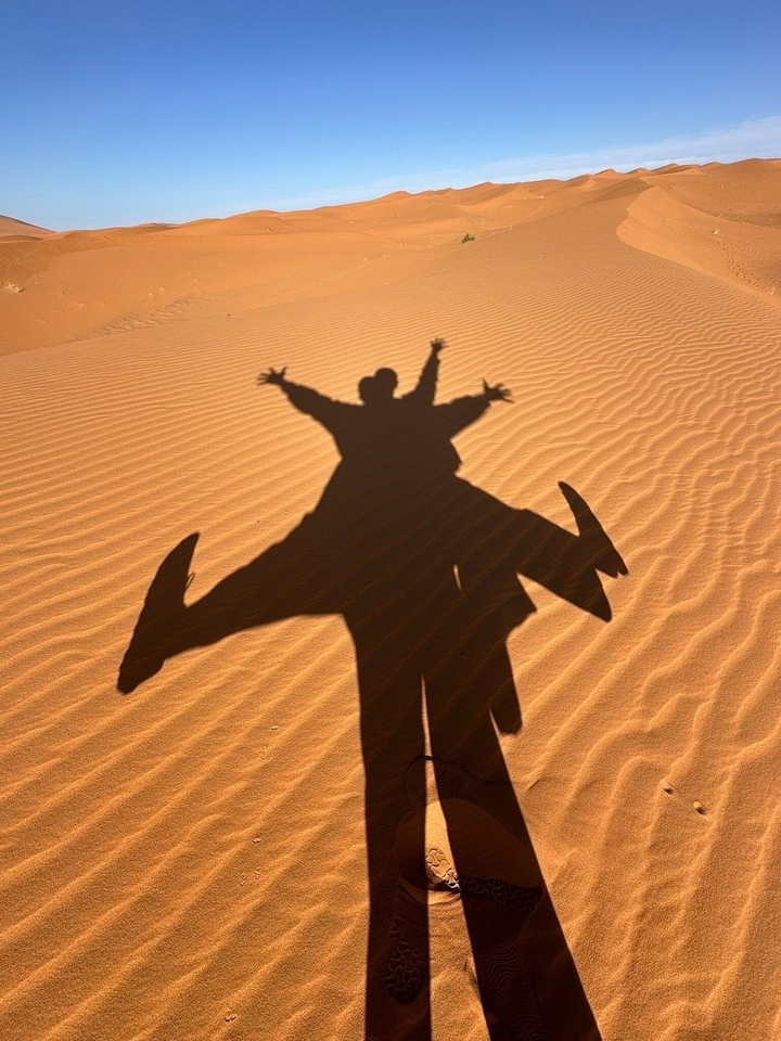 Ombres de deux personnes sautant sur des dunes de sable.