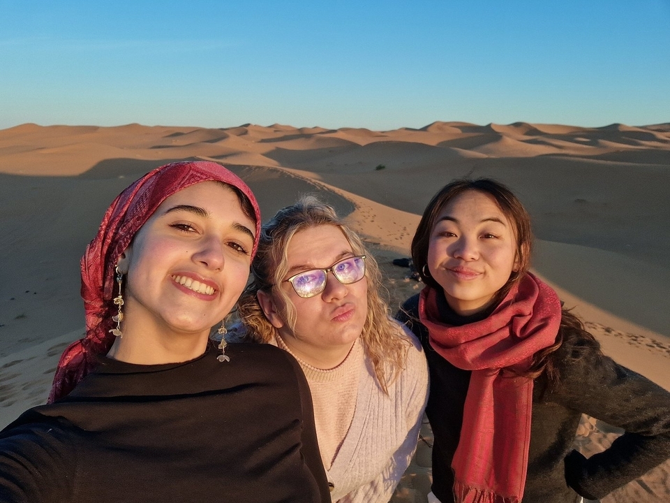 Trois personnes posant et souriant dans un environnement désertique.