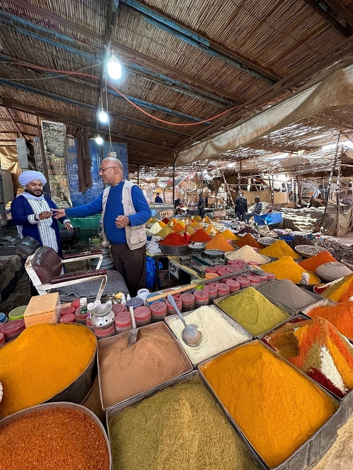 Marché aux épices coloré avec des hommes qui interagissent autour des épices.