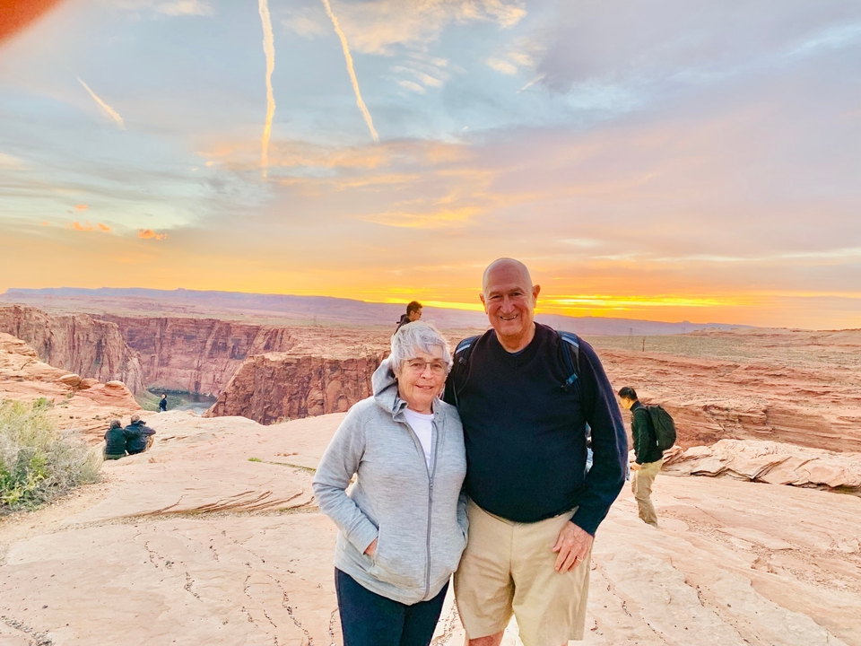 Un couple qui pose avec un canyon et un coucher de soleil en arrière-plan.