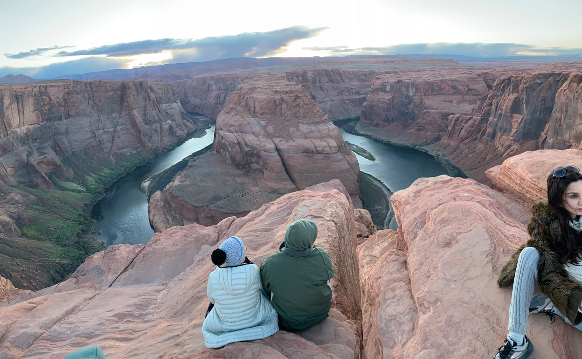 Des gens assis au bord d'un canyon avec une rivière en contrebas.