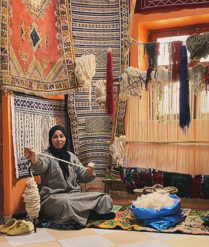 Femme travaillant avec de la laine dans un cadre textile traditionnel.