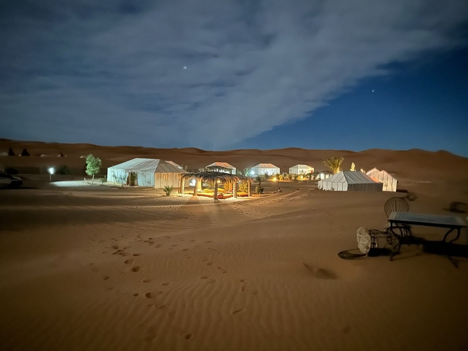 Camp du désert avec des tentes éclairées la nuit.