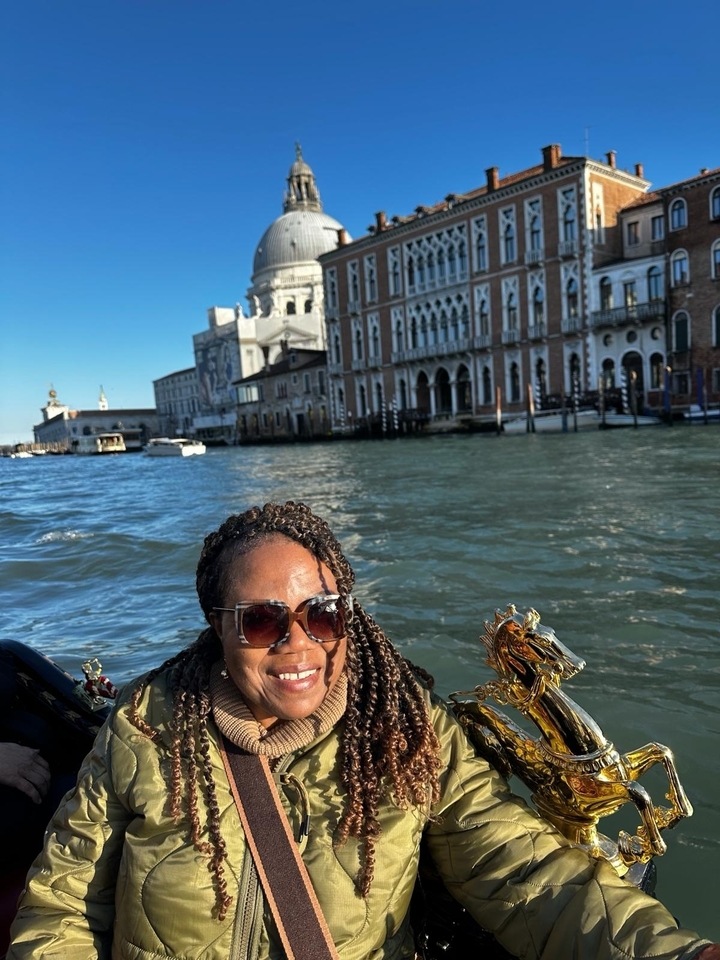 Personne sur un bateau dans un canal avec des bâtiments historiques en arrière-plan.