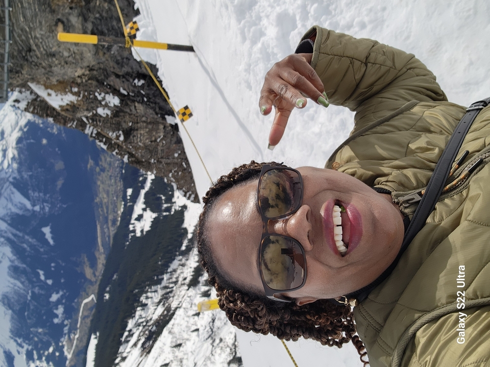 Personne souriante, posant dans un décor de montagne enneigée.