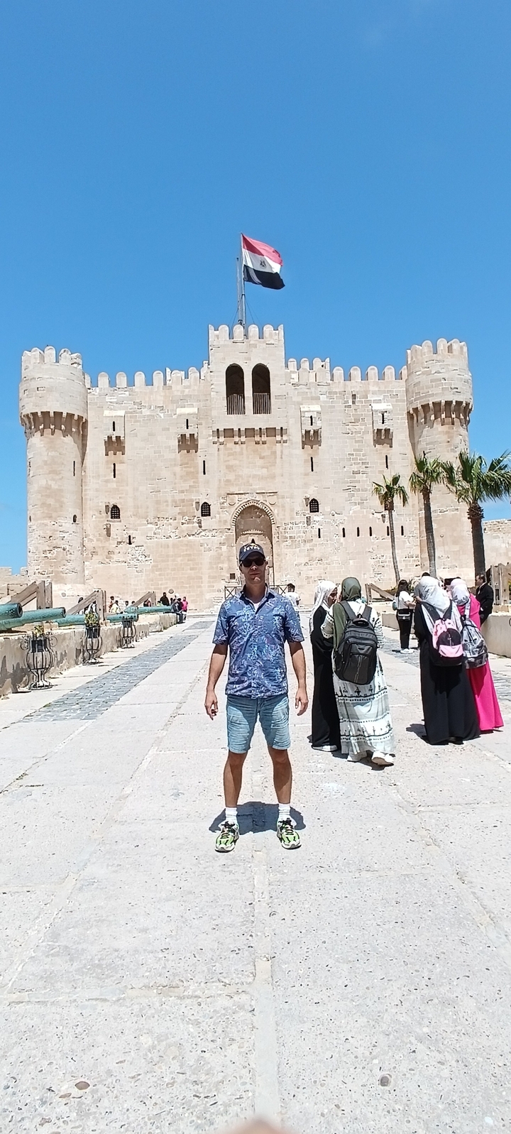 Personne debout devant une forteresse historique avec d'autres touristes.