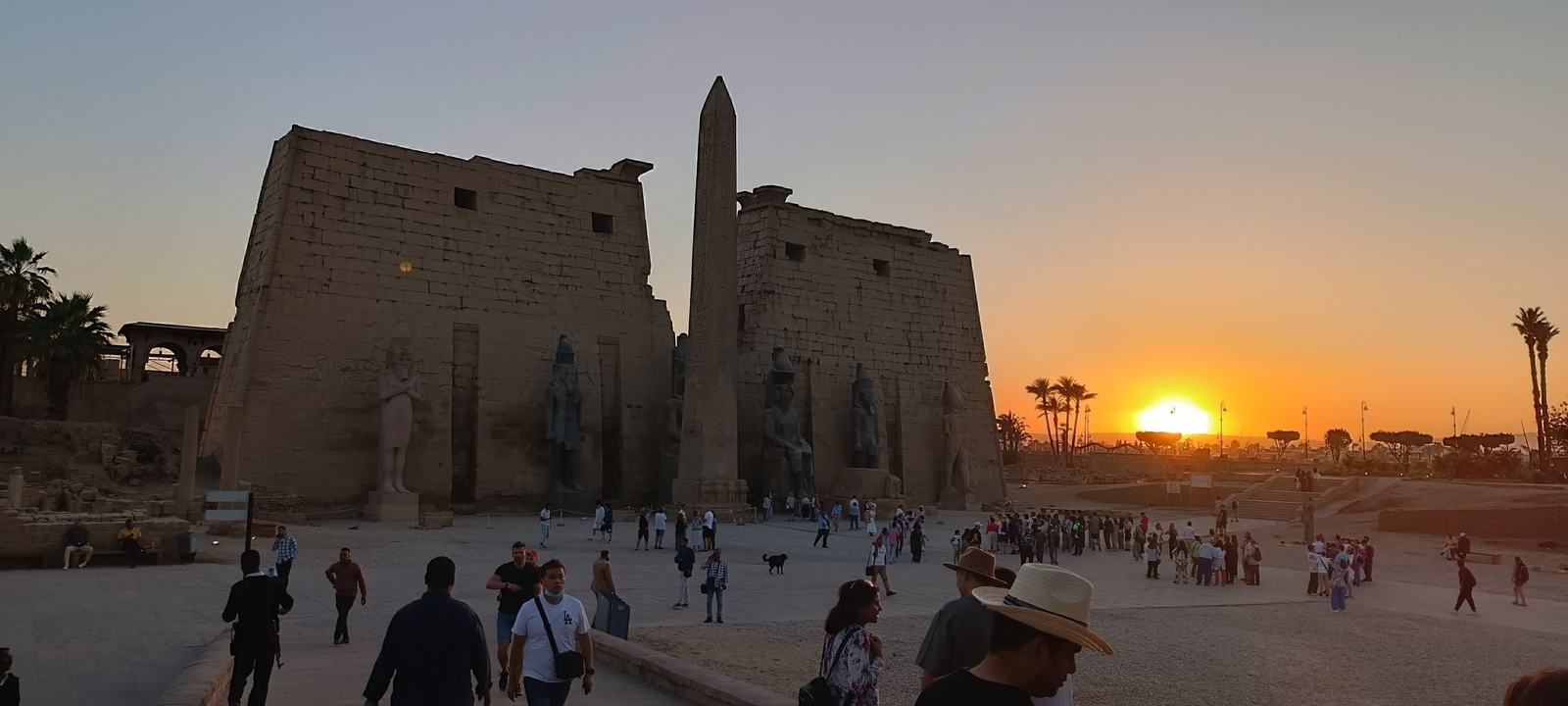 Vue du coucher de soleil d'un complexe de temples historiques avec de nombreux visiteurs.