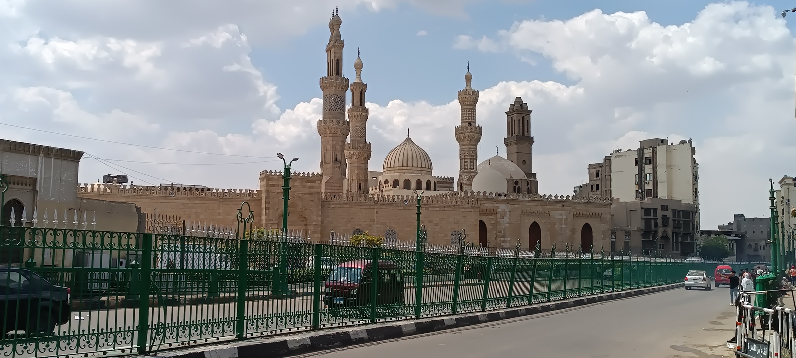 Vue d'une mosquée avec plusieurs minarets dans un environnement urbain.