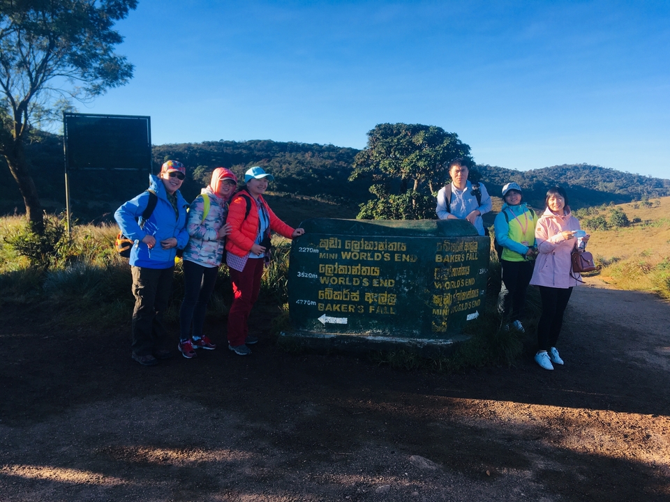Groupe de personnes posant avec un panneau directionnel dans une zone montagneuse.