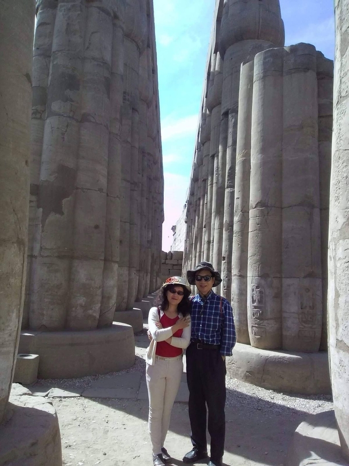Couple posant dans les ruines d'un temple antique avec de hautes colonnes.