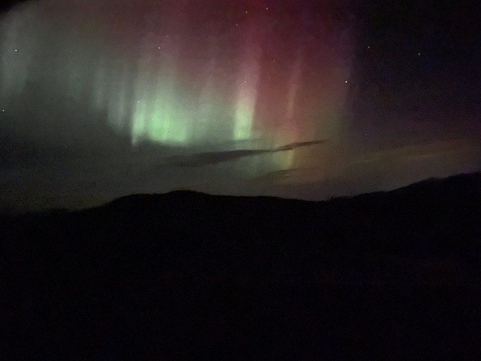 Aurores boréales au-dessus d'un paysage sombre.