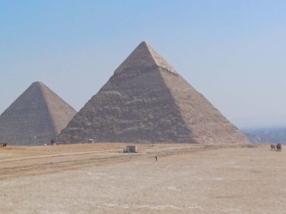 Deux pyramides se dressant sur un paysage sablonneux.