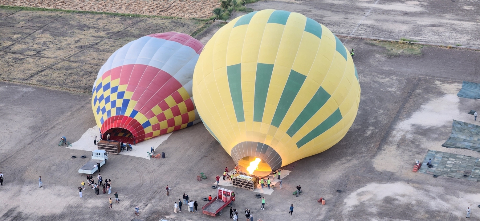 Des montgolfières en préparation pour le vol près de champs herbeux.