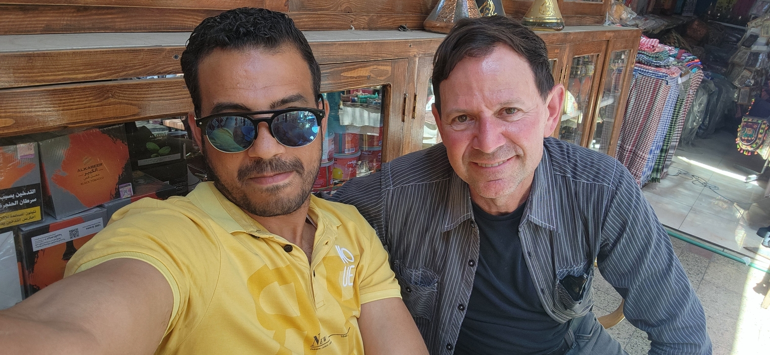 Deux hommes assis ensemble à un marché en plein air ou dans un café.