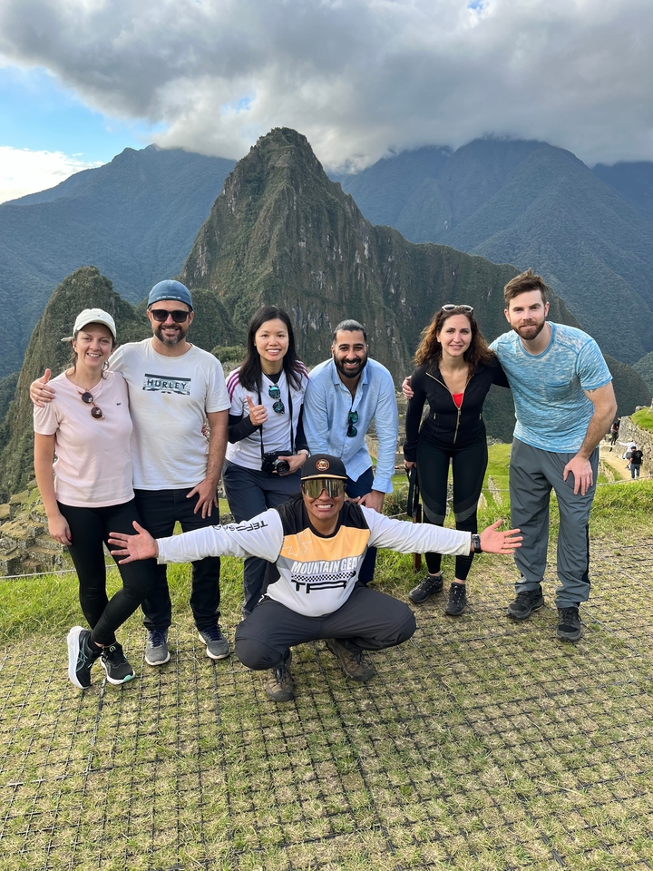 Gruppe von Wanderern, die an einem malerischen Aussichtspunkt mit Bergen posieren.