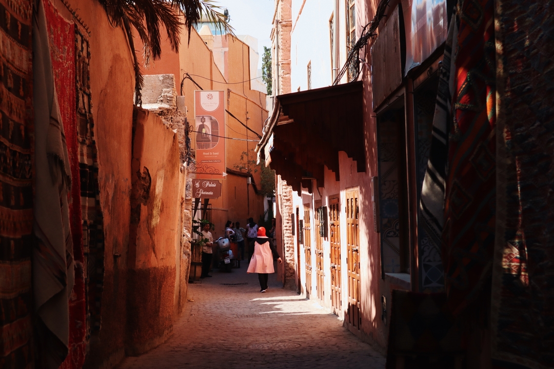 Une ruelle étroite avec des magasins et une femme qui marche.