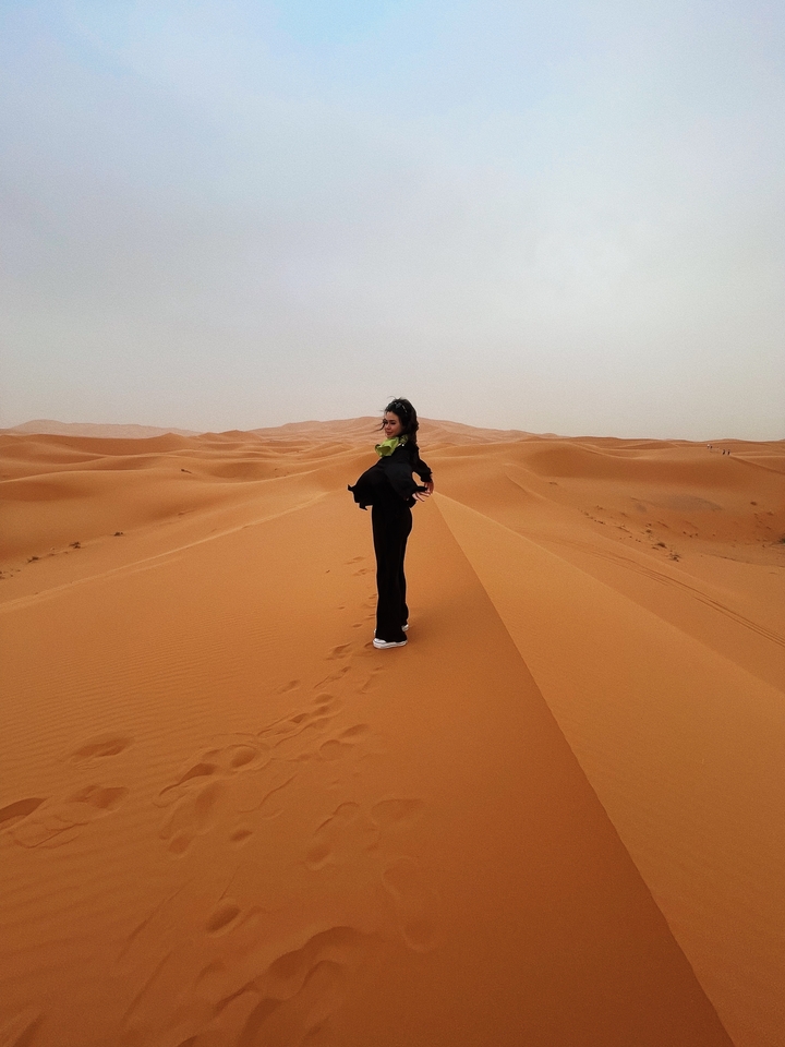 Une femme qui pose sur des dunes de sable.