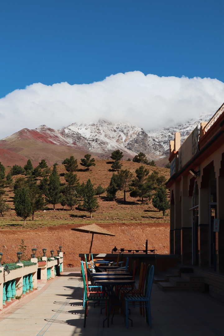 Montagnes bordées d'arbres partiellement couvertes de neige à côté d'un bâtiment.