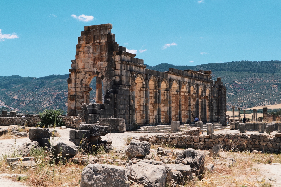 Ruines antiques avec des arches dans un paysage montagneux.