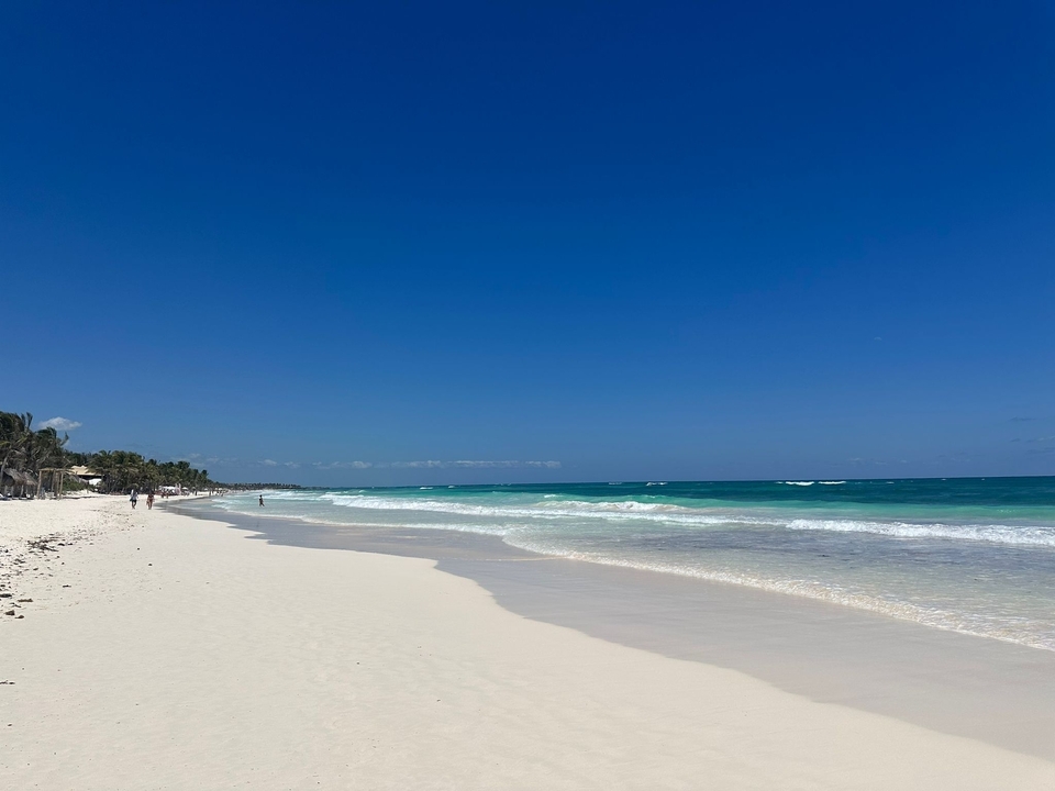 Plage immaculée avec du sable blanc et une eau bleue cristalline.