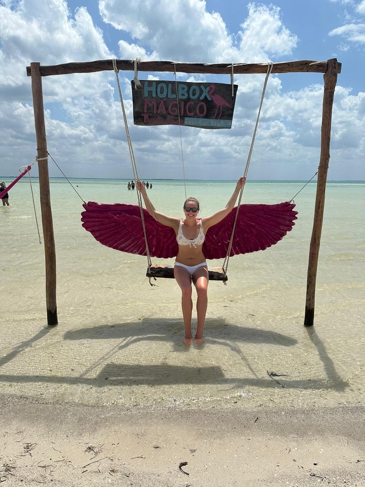 Femme sur une balançoire au-dessus d'une eau turquoise peu profonde.