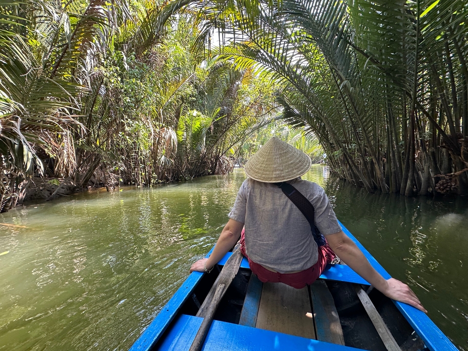 Personne sur un bateau ramant à travers une rivière bordée d'arbres denses.