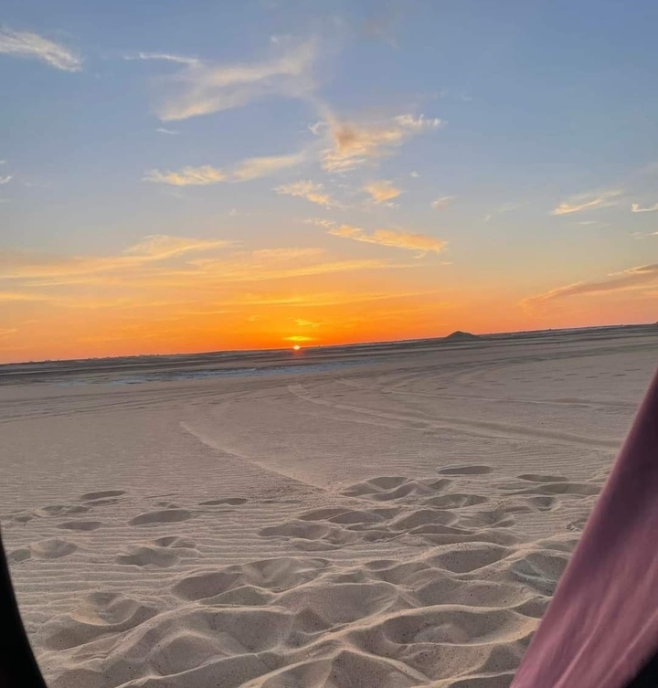 Coucher de soleil sur les dunes de sable avec un ciel dégagé.
