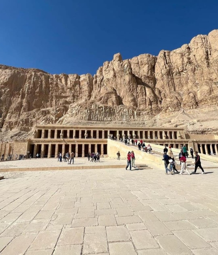 Touristes dans un temple historique avec des falaises spectaculaires.