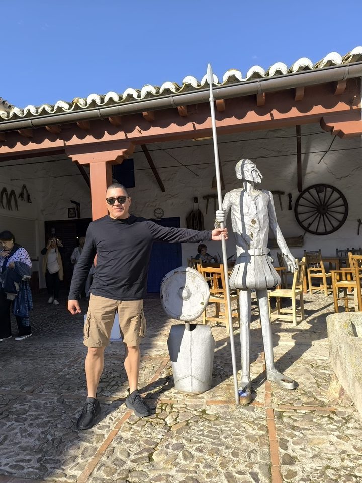 Homme posant à côté d'une statue originale devant un café.