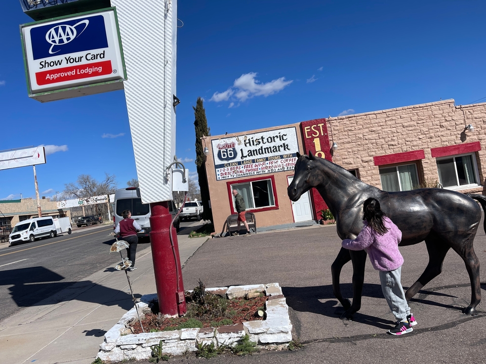 Scène de rue avec un panneau historique emblématique de la Route 66 et une statue.