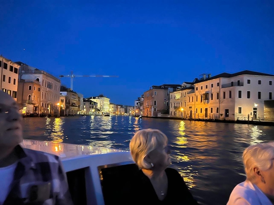 Un canal à Venise pendant la nuit avec des bâtiments illuminés.