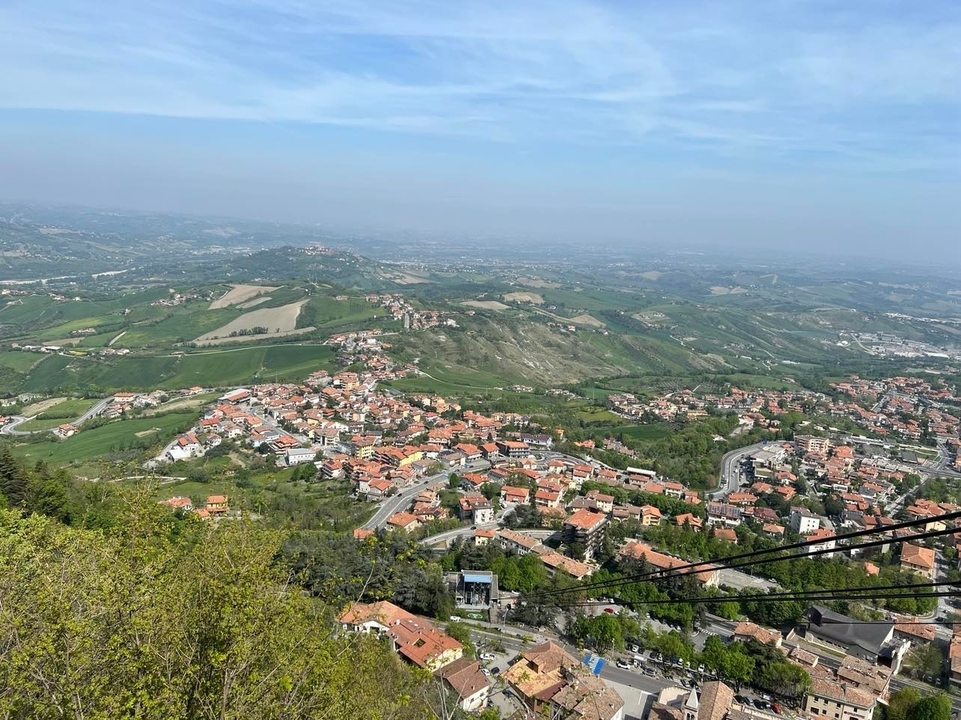 Vue aérienne d'une ville entourée de collines vertes et de champs.