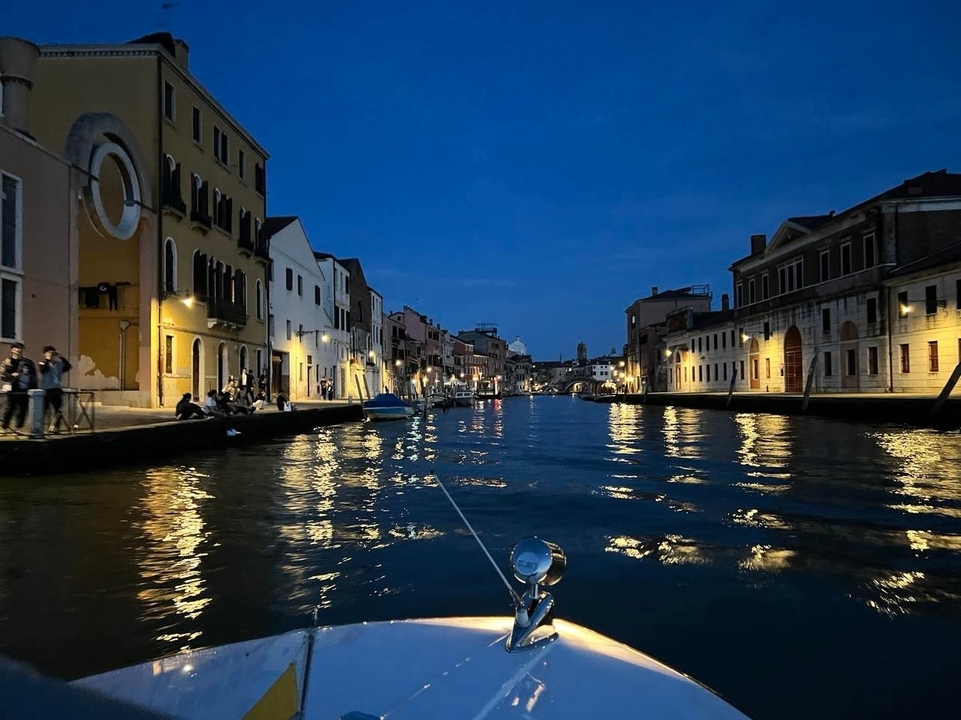 Vue nocturne d'un canal à Venise avec des reflets sur l'eau.