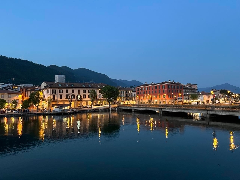 Une ville sereine au bord d'un lac avec des bâtiments se reflétant sur l'eau au crépuscule.