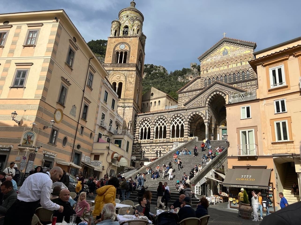 Une place animée avec une grande cathédrale et de nombreux visiteurs.