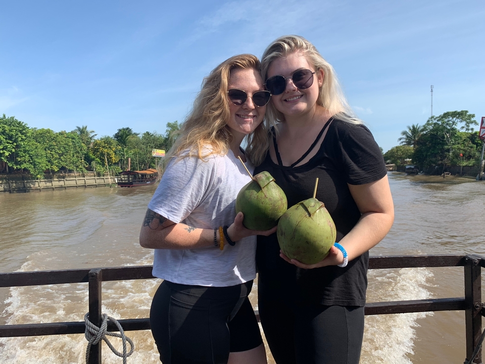 Deux personnes tenant des noix de coco sur un bateau.