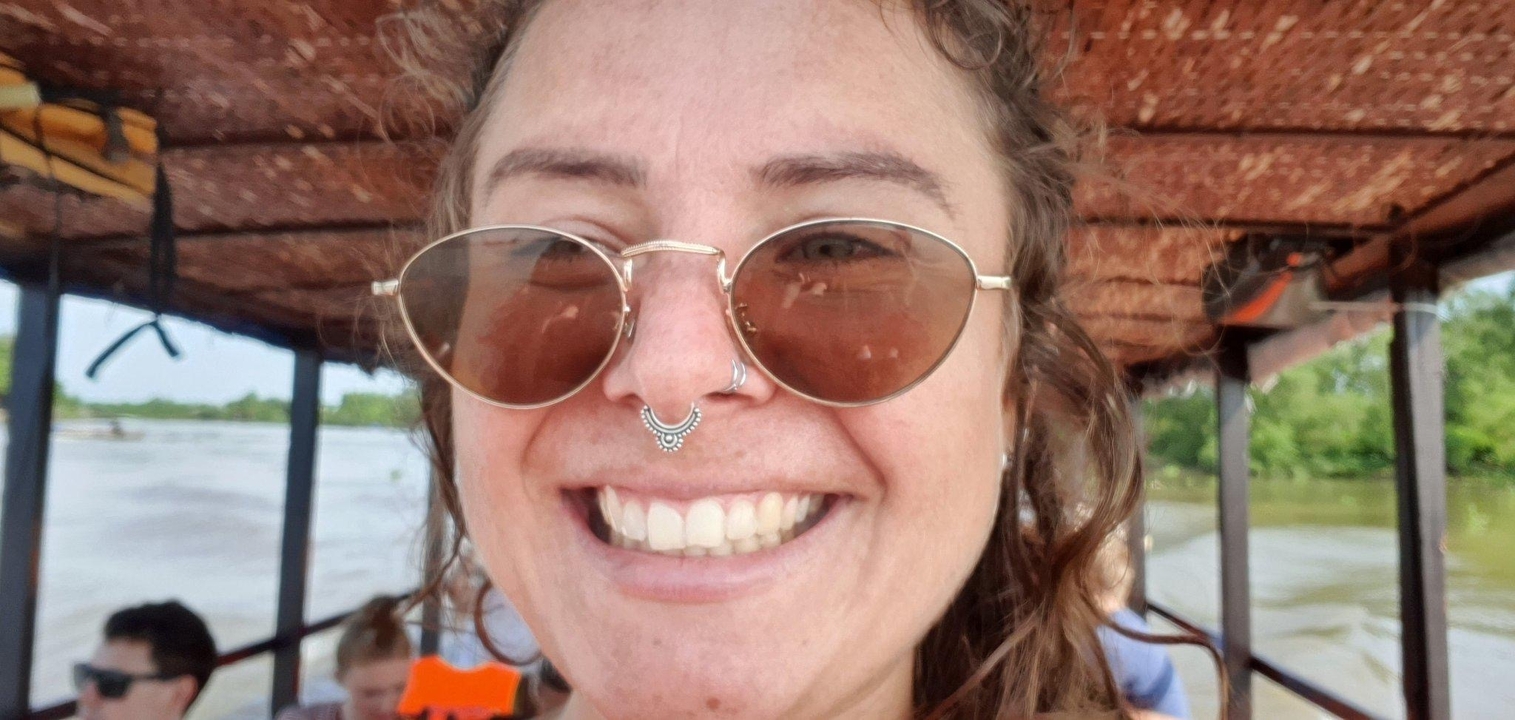 Gros plan d'une personne souriante portant des lunettes de soleil sur un bateau.