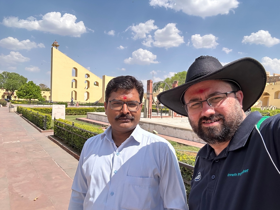 Deux hommes sur un site extérieur avec des structures historiques.