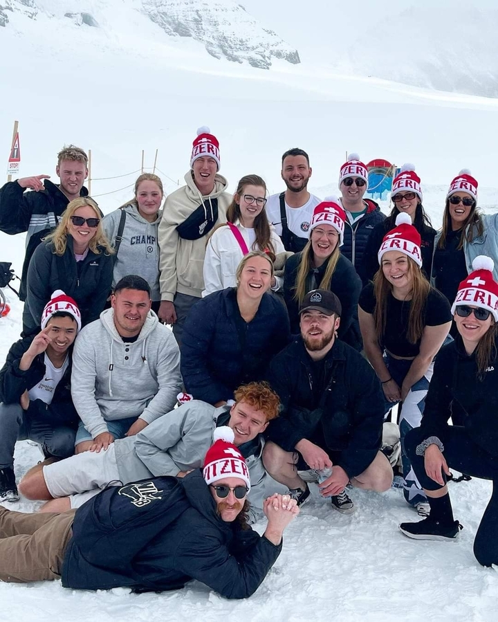Un groupe de personnes posant dans la neige portant des chapeaux à thème suisse.