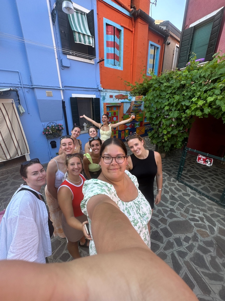 Groupe de personnes posant avec des murs colorés et de la verdure en arrière-plan.