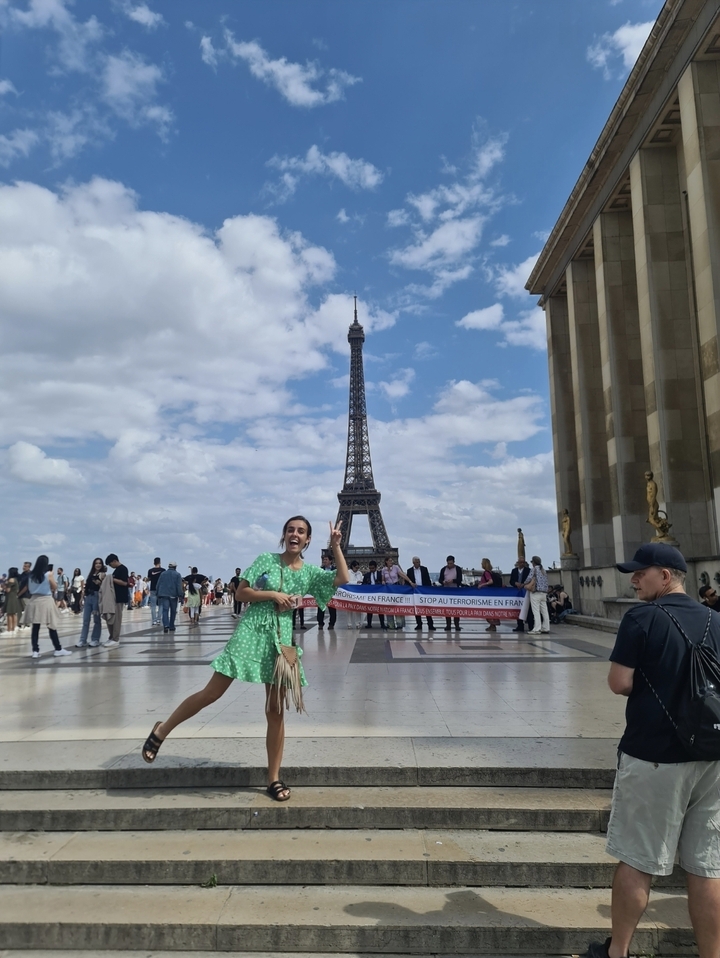 Personne posant avec la Tour Eiffel en arrière-plan et des gens autour.