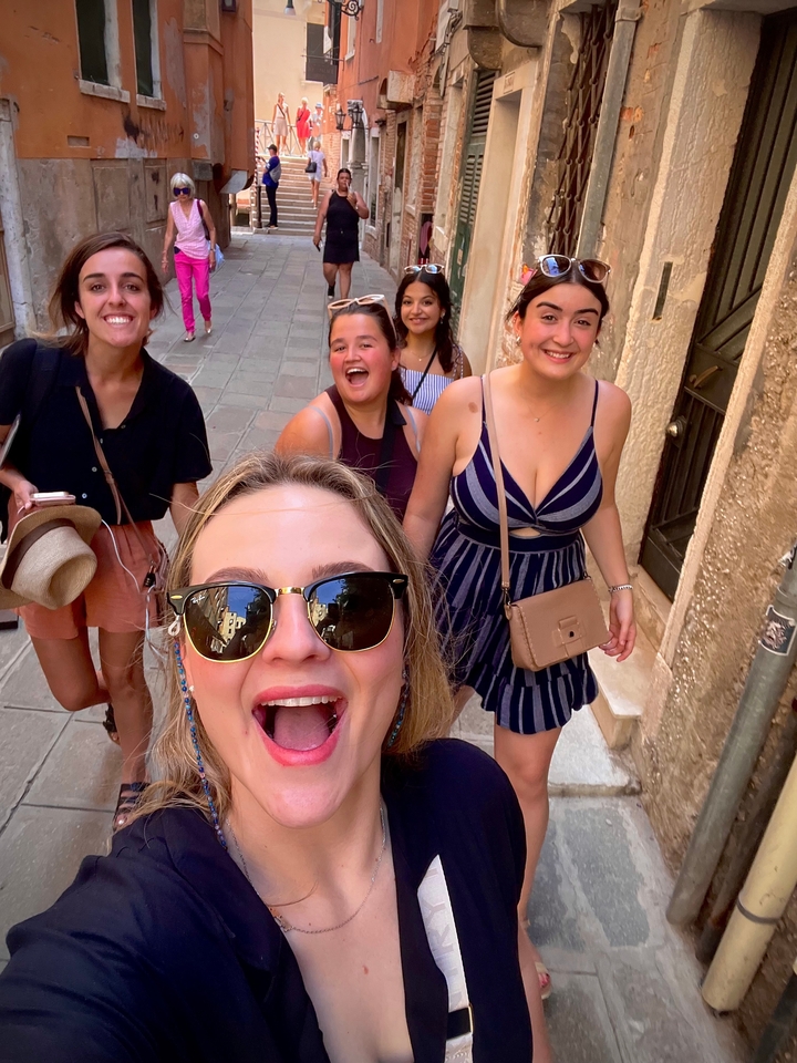 Groupe d'amis souriants marchant dans une vieille rue.