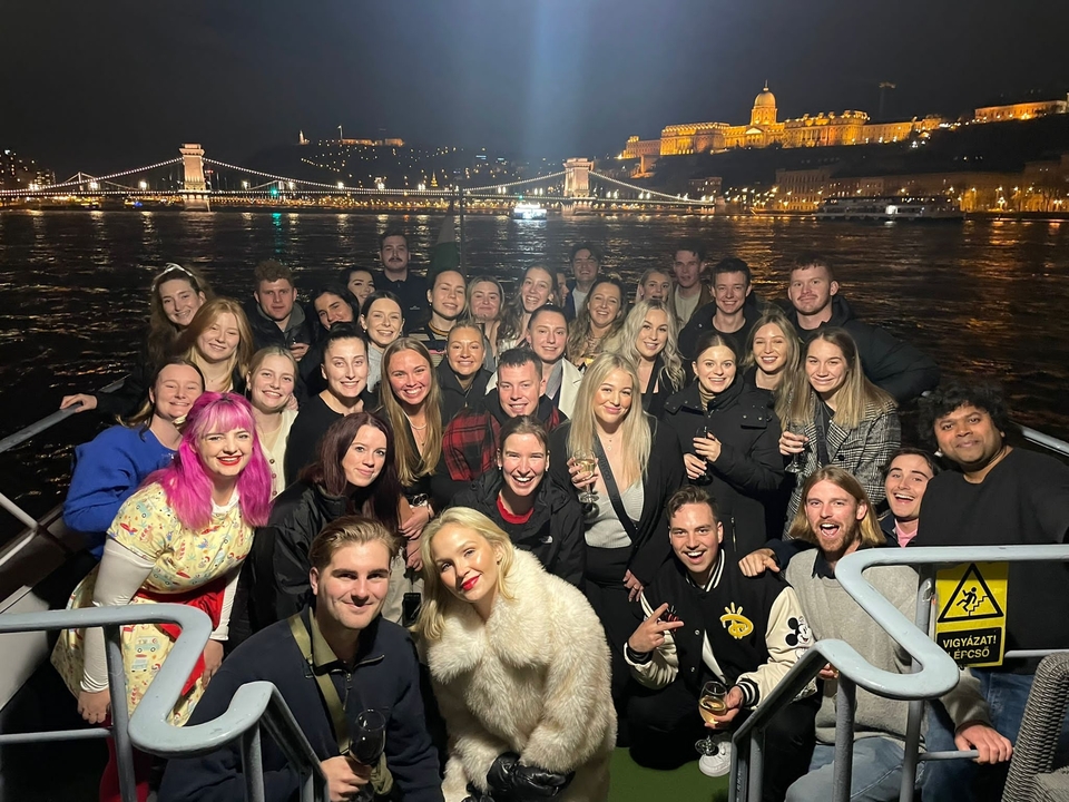 Groupe de personnes lors d'une croisière nocturne avec les lumières de la ville en arrière-plan.