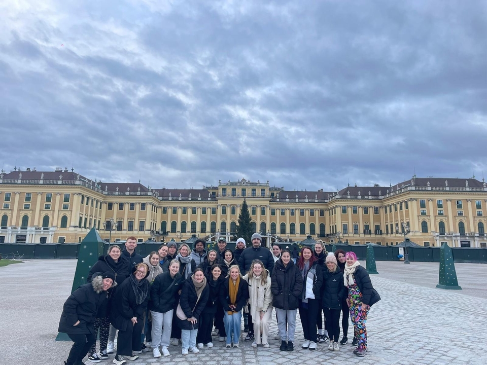 Grand groupe posant devant un palais par temps nuageux.