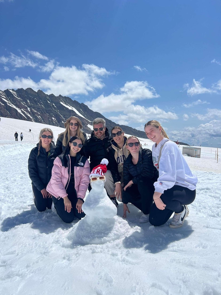 Groupe de personnes dans la neige avec un bonhomme de neige.